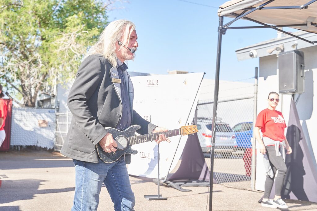 Capstone Contributes event emcee playing guitar during community celebration
